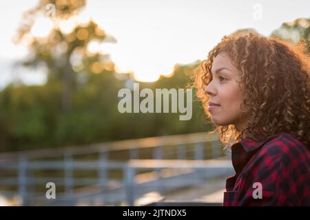 Frau in ihren Dreißigern, die denkt, als die Sonne untergeht. Hochwertige Fotos Stockfoto