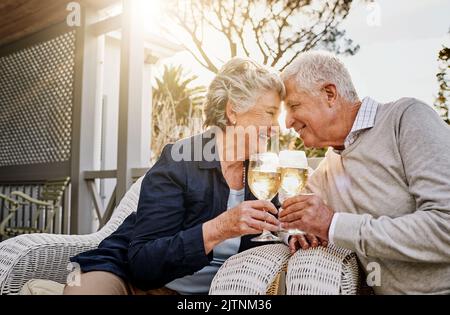 Möge unsere Liebe weiter wachsen. Ein glückliches Seniorenpaar, das an einem gemütlichen Nachmittag draußen mit Wein rösten kann. Stockfoto