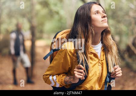 Wellness, Natur und Abenteuer mit einer Backpacker-Frau erkunden Sie einen Wald, atmen frische Luft ein und schauen sich um. Junge Frau genießt den Blick auf die Stockfoto