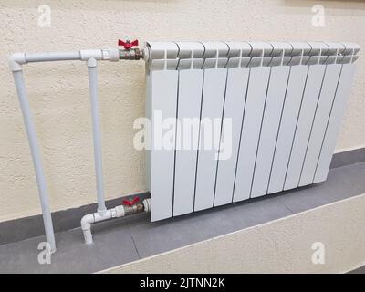 Weiße moderne Aluminium-Heizkörperbatterie für Warmwasserbereitung, auf dem Hintergrund einer Wand im Inneren einer Wohnung oder eines Büros. Stockfoto