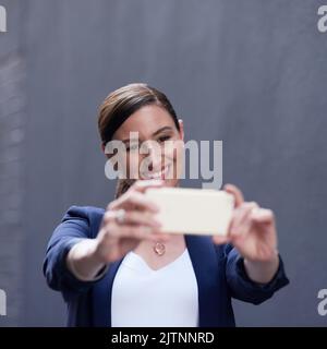 Spaß mit ihrem neuesten Tech-Spielzeug. Eine glückliche Geschäftsfrau, die Spaß mit ihrem Smartphone hat. Stockfoto