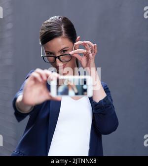 Es gibt immer Zeit für ein Selfie. Eine glückliche Geschäftsfrau nimmt ein lustiges Selfie mit ihrem Smartphone. Stockfoto