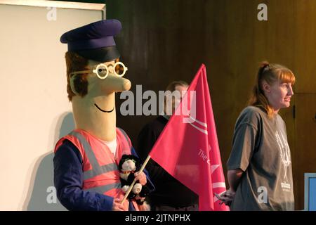 London, Großbritannien. 31.. August 2022. Eine als Kinderfernsehfigur verkleidete Person, Postman Pat, tritt bei der Transport-Kundgebung der Transportgewerkschaft Save London im Kongresshaus auf, weil die staatlichen Mittel für den TfL nicht ausreichen, was zu Stellenabbau und höheren Preisen führt, wenn sich die Lebenshaltungskosten verschärfen. Kredit: Elfte Stunde Fotografie/Alamy Live Nachrichten Stockfoto