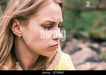 Seitenansicht Porträt einer jungen, ernsthaft verärgerten Frau, die ihre Zähne mit einem angespannten Kiefer zusammenklemmte. Stockfoto