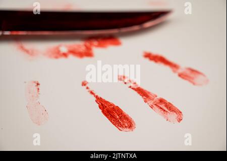 Blutige Messer- und Handdrucke in Blut auf einem weißen Tisch. Stockfoto