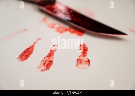 Blutige Messer- und Handdrucke in Blut auf einem weißen Tisch. Stockfoto