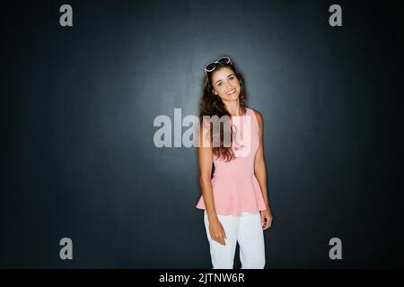 Hübsch in Pink. Studioportrait einer jungen Frau, die vor dunklem Hintergrund posiert. Stockfoto