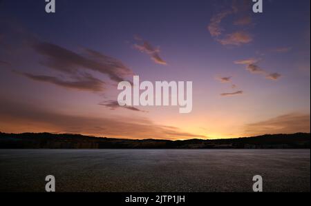 Leerer Asphaltboden mit wunderschönem Sonnenuntergangshimmel Stockfoto