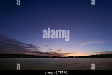 Leerer Asphaltboden mit wunderschönem Sonnenuntergangshimmel Stockfoto