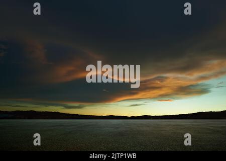 Leerer Asphaltboden mit wunderschönem Sonnenuntergangshimmel Stockfoto