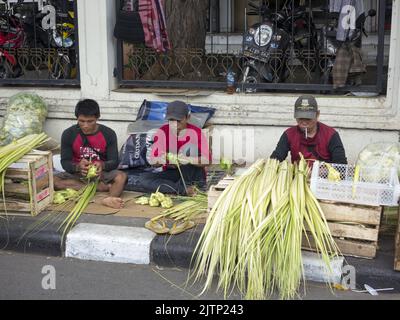 Jakarta, Indonesien-5. Juli 2022: Ketupat-Händler machen Ketupat am Straßenrand. Ketupat oder Tipat ist ein javanesischer Reiskuchen, der in einem Diamantschapf verpackt ist Stockfoto