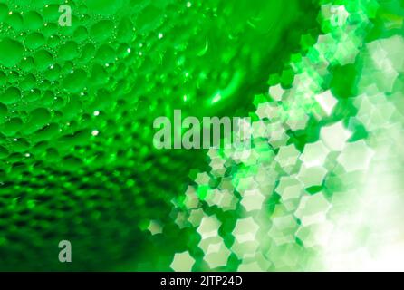 Grüne Glasflasche, selektiver Fokus, schönes unscharfes Bokeh. Nahaufnahme. Wassertropfen auf dem Glas, die in Form einer sechseckigen M in das Bokeh übergehen Stockfoto