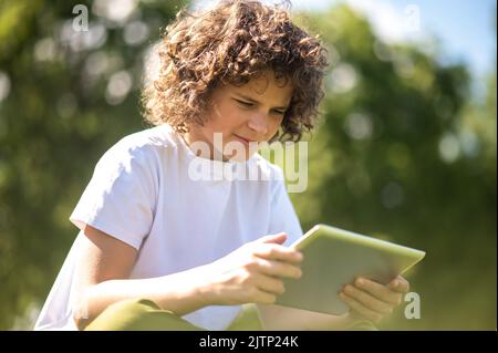 Fokussierter Jugendlicher, der das Gadget in seinen Händen ansieht Stockfoto