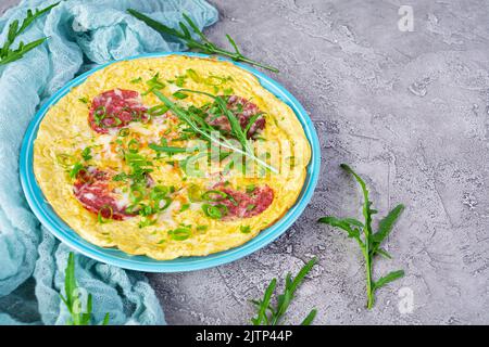 Omelette mit Wurst, Kräutern und geriebenem Käse. Einfaches Frühstück Stockfoto