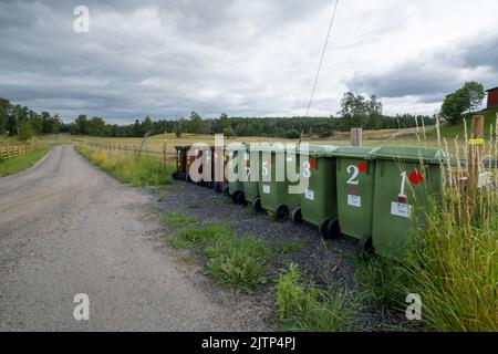 Die Mülltonnen befinden sich entlang der Landstraße. Stockfoto