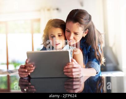 Die Wunder des World Wide Web. Eine Mutter und Tochter, die zu Hause ein digitales Tablet benutzen. Stockfoto