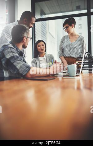 Gemeinsam vorwärts: Eine Gruppe von Geschäftsleuten scharten sich in ihrem Büro um einen Laptop. Stockfoto