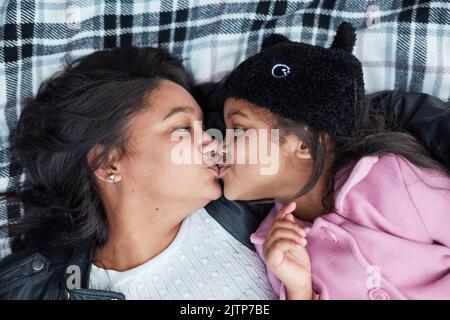 Es ist die besondere Bindung, die nur Mütter und Töchter haben. Ein kleines Mädchen und ihre Mutter verbinden sich, während sie draußen auf einer Decke liegen. Stockfoto