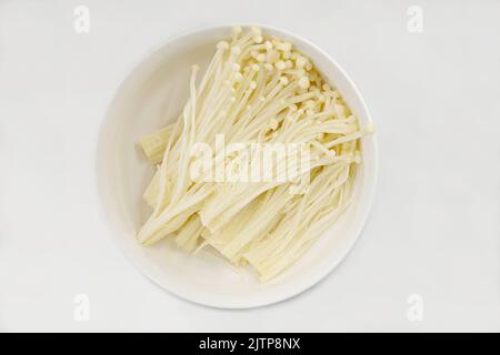 Eine Schale aus kultiviertem Enoki- oder Golden-Nadel-Pilz, Flammulina filiformis, vor weißem Hintergrund Stockfoto