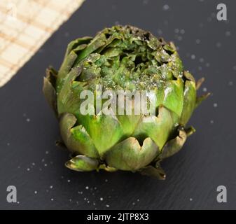 Gekochte Artischocken auf schwarzem Steinbrett Stockfoto