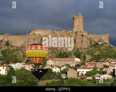 Heißluftballon, der in der Nähe einer mittelalterlichen Festung auf einer vulkanischen mesa schwebt. Polignac, Haute-Loire, Auvergne-Rhône-Alpes, Frankreich. Stockfoto