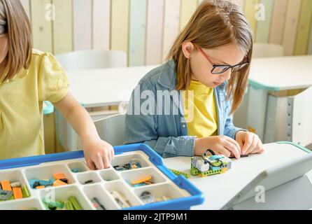 Programmierarbeit, Robotik in der Grundschule lernen. Kinder Studenten Montage, Start, Codierung des Roboters. Konstruktorteile nach Anweisungen in ta Stockfoto