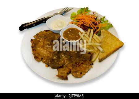 Das Schweinestieb-Steak mit gebratenem französischem steak würzen und Gemüse auf weißem, isoliertem Steak mischen. Stockfoto