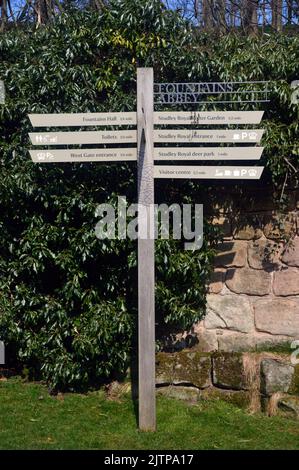 Hölzerner Wegweiser auf dem Gelände der Ruinen des Fountains Abbey Zisterzienserklosters, North Yorkshire, England, Großbritannien. Stockfoto