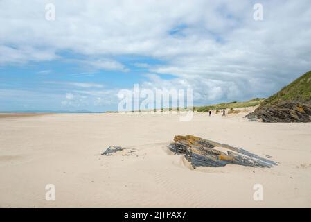 Spaziergänger am Strand von Morfa Bychan bei Porthmadog an der Küste von Nord-Wales. Stockfoto