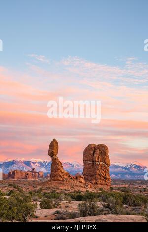 Farbenfrohe Wolken über den La Sal Bergen bei einem Blick nach Sonnenuntergang auf Balanced Rock im Arches National Park, Moab, Utah. Stockfoto