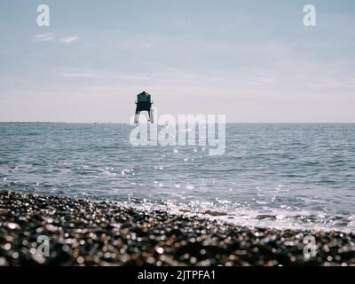 Der Dovercourt Victorian Low Lighthouse und Sommer Kiesstrand und glitzerndes Meer in Harwich in Essex England - Sommer Leuchtturm Küste Stockfoto