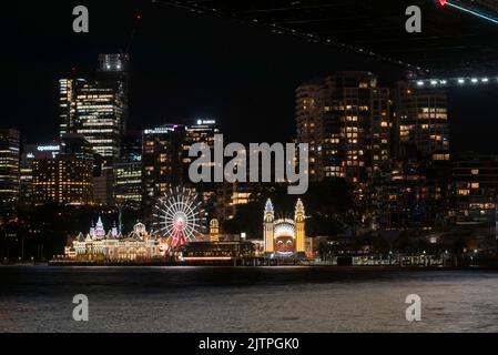 Das gruselig lächelnde Gesicht, das Riesenrad und der Rest des Luna Park am Hafenvorland in Sydney, beleuchtet während des Vivid Sydney 2022 in Australien Stockfoto