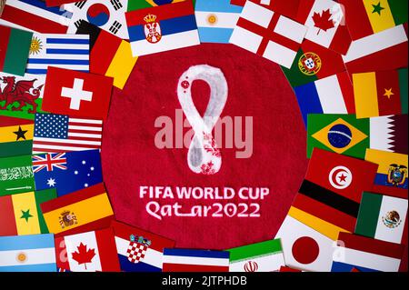 DOHA, KATAR, 30. AUGUST 2022: Flaggen aller 32 Teams, die am FIFA Fußball-Weltmeisterschaft Qater 2022 teilnehmen. Offizielles Logo des Fußballturniers auf rotem Hintergrund Stockfoto