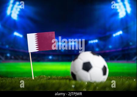 Qatar Mini Flagge und Fußball. Sport Fußball Wallpaper. Fußballstadion in der Nacht im Hintergrund Stockfoto