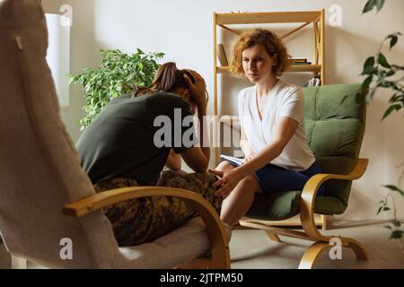 Psychologe führt Behandlung, Gespräch mit jungen Mädchen, ehemaliger Militärangehöriger im Büro, in Innenräumen. Konzept der psychischen Gesundheit, posttraumatisch Stockfoto