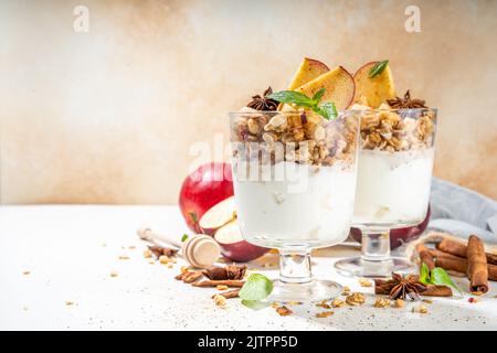 Apfelkuchen Müsli Käsekuchen, Frühstückssnack geschichtet Dessert mit Hafergranola, Frischkäse Joghurt, Honig, Apfelscheiben und Zimt Gewürze auf weiß Stockfoto