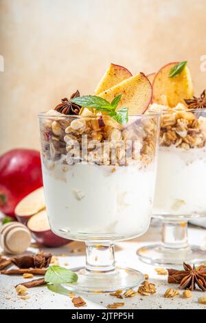 Apfelkuchen Müsli Käsekuchen, Frühstückssnack geschichtet Dessert mit Hafergranola, Frischkäse Joghurt, Honig, Apfelscheiben und Zimt Gewürze auf weiß Stockfoto