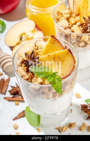 Apfelkuchen Müsli Käsekuchen, Frühstückssnack geschichtet Dessert mit Hafergranola, Frischkäse Joghurt, Honig, Apfelscheiben und Zimt Gewürze auf weiß Stockfoto