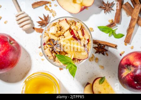 Apfelkuchen Müsli Käsekuchen, Frühstückssnack geschichtet Dessert mit Hafergranola, Frischkäse Joghurt, Honig, Apfelscheiben und Zimt Gewürze auf weiß Stockfoto