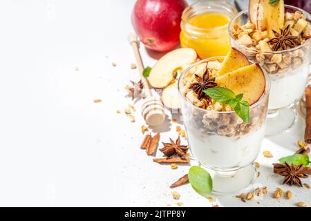 Apfelkuchen Müsli Käsekuchen, Frühstückssnack geschichtet Dessert mit Hafergranola, Frischkäse Joghurt, Honig, Apfelscheiben und Zimt Gewürze auf weiß Stockfoto