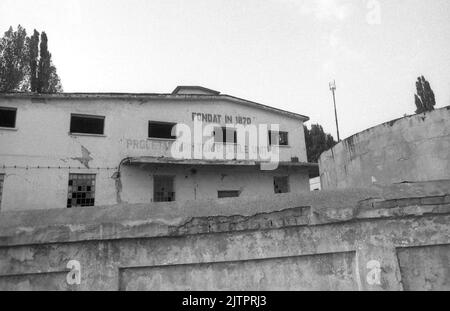 Verlassene Fabrik in Rumänien, ca. 1992. An der Fassade sind noch zwei Inschriften zu sehen: 'Gegründet 1870' und der kommunistische Slogan 'Arbeiter der Welt, vereinigt euch'. Stockfoto