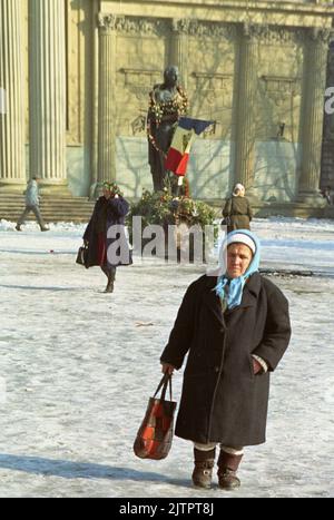 Bukarest, Rumänien, Januar 1990. Wenige Wochen nach der rumänischen Revolution von 1989 werden Blumen um die Statue des 'nationalen' Dichters Mihai Eminescu vor dem Athen aufgestellt. Die Nationalflagge mit dem abgeschnittenen sozialistischen Emblem wurde während der Revolution zu einem Symbol, das das Ende der kommunistischen Ära darstellt. Stockfoto