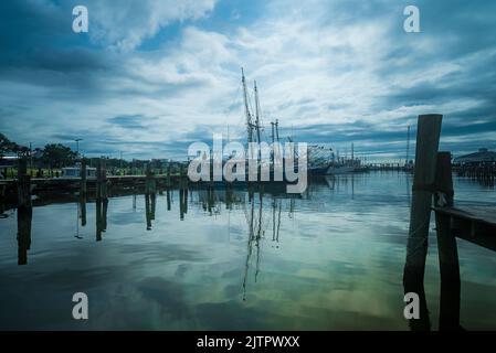 Der Blick auf angedockte Boote unter dem wolkigen Himmel, der sich im Hafen von Pass Christian auf dem Wasser spiegelt Stockfoto