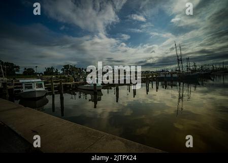 Der Blick auf angedockte Boote unter dem wolkigen Himmel, der sich im Hafen von Pass Christian auf dem Wasser spiegelt Stockfoto