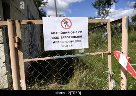 REGION KIEW, UKRAINE - 01. SEPTEMBER 2022 - Vor dem von russischen Beschuss zerstörten Kindergarten in der Gemeinde Makariv, Region Kiew, Nord-Zentral-Ukraine, Ist Ein Warnschild zu sehen. Stockfoto