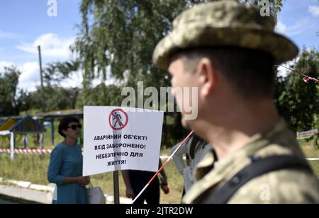 REGION KIEW, UKRAINE - 01. SEPTEMBER 2022 - Vor dem von russischen Beschuss zerstörten Kindergarten in der Gemeinde Makariv, Region Kiew, Nord-Zentral-Ukraine, Ist Ein Warnschild zu sehen. Stockfoto