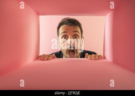 Der überraschte Mann packte aus, öffnete den Karton und schaute hinein. Stockfoto