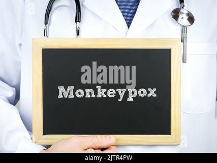 Arzt hält eine Tafel mit einer Botschaft von Monkeypox Stockfoto