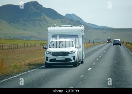 Island, Sudurland - August 8., 2022 - Auto schleppen einen Anhänger auf einer Straße. Stockfoto