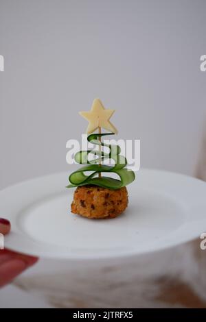 Eine Gurke, die wie ein Weihnachtsbaum auf einem Cocktailstab aussieht, der in ein Sandwich mit einem Käsestern geschoben wird. Stockfoto